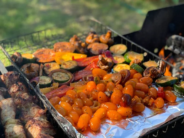 Izgara sebzeler yakın plan. Domates, mantar ve biber, yakın plan kabak ızgarada pişirilir, ateşin üzerinde tütsülenir..