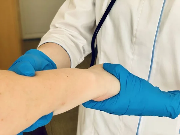 青い医療用手袋の医者は患者の手を感じる — ストック写真