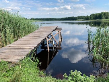 Göl manzarası, bulutlu mavi gökyüzü. Göldeki tahta patika..