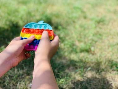 Patlat. Çok renkli, stres önleyici oyuncak bir çocuğun ellerinde..
