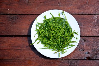 ahşap arka plan üzerinde yabani kuşkonmaz içeren beyaz tabak