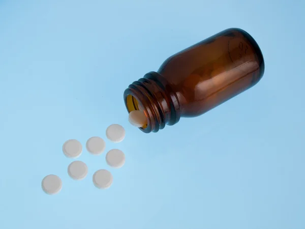 Białe tabletki wylewa z butelki — Zdjęcie stockowe