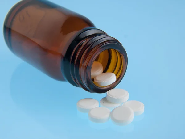 Białe tabletki wylewa z butelki — Zdjęcie stockowe
