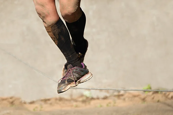 Man walking egy kötélen a sár racevisible csak lábak — Stock Fotó