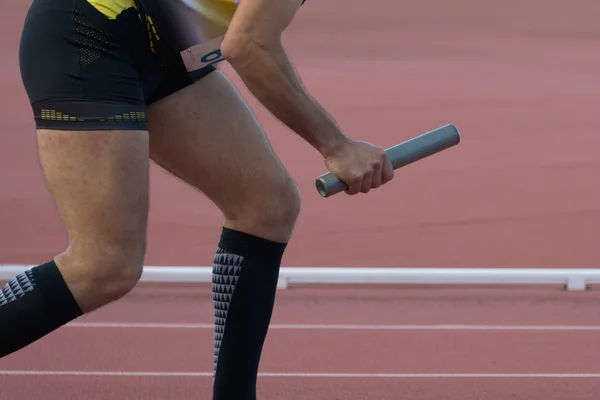 Homem atlético correndo um relés a pista de atletismo — Fotografia de Stock