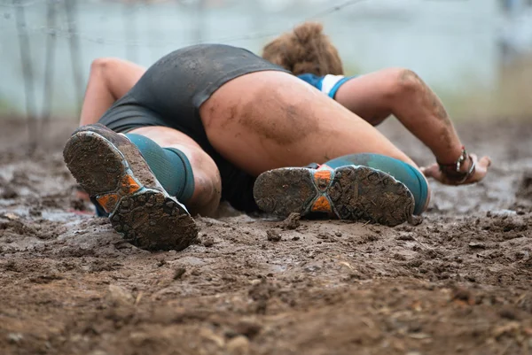 Kruipen, passeren onder een prikkeldraad obstakels tijdens extreme obstakel race — Stockfoto