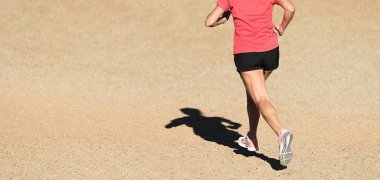 Dağ ortamında spor ayakkabılarıyla çakıl yolda koşan bir kadın.