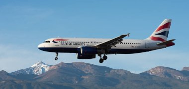 Tenerife, İspanya 31 Aralık 2025. Airbus A320-232 British Airways Airlines mavi gökyüzünde uçuyor. Tenerife Havaalanına iniyor. Arka planda El Teide volkanı var.