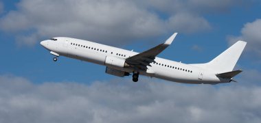 Uçak mavi gökyüzünde beyaz bulutlarla havalanıyor. Arka planda uçan uçaklar. Mavi gökyüzünde beyaz yolcu uçağı. Mavi gökyüzünün altında, beyaz bulutlarla uçan uçağın alçak açılı görüntüsü