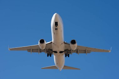 Uçak iniyor. Uçak, mavi gökyüzünde uçan yolcular, havaalanına inmeye hazırlanıyorlar. Aşağıdan görüntüle