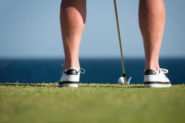 Pelota de golf y palo con piernas de golfista en primer plano en el océano de fondo — Foto de Stock