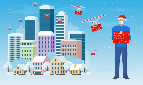 Drone szállítási karácsonyi ajándék és Courier egy arc maszk és egy karácsonyi kalap egy doboz a kezében a városban, és a hó esik. Hazaviszem. Ajándékok fényes dobozokban. Téli város. — Stock Vector