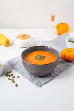 Beyaz ahşap arka planda kabak tohumlu kavrulmuş balkabağı çorbası. Uzayı kopyala Sonbahar havası. Dikey yönelim