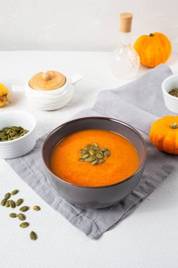 Beyaz ahşap arka planda kabak tohumlu kavrulmuş balkabağı çorbası. Uzayı kopyala Sonbahar havası. Dikey yönelim