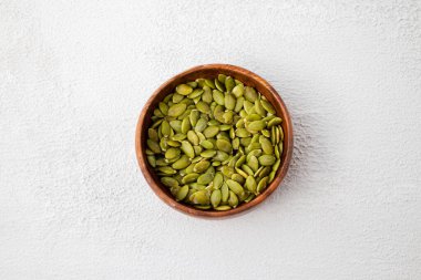 Ahşap kasede kavrulmuş balkabağı tohumlarının üst görüntüsü. Beyaz arka plan bombardımanından sonra Pepita 'yı kurut. Yatay