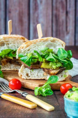 Salatalık turşulu biftekli sandviç, ezilmiş avokado ve yeşil yaprak salatası.