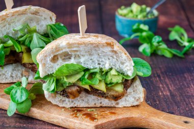 Salatalık turşulu biftekli sandviç, ezilmiş avokado ve yeşil yaprak salatası.