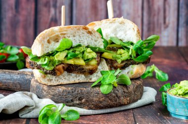 Salatalık turşulu biftekli sandviç, ezilmiş avokado ve yeşil yaprak salatası.