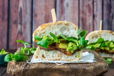 Salatalık turşulu biftekli sandviç, ezilmiş avokado ve yeşil yaprak salatası.