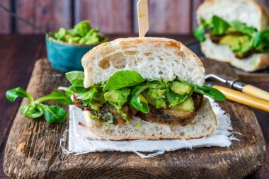 Salatalık turşulu biftekli sandviç, ezilmiş avokado ve yeşil yaprak salatası.