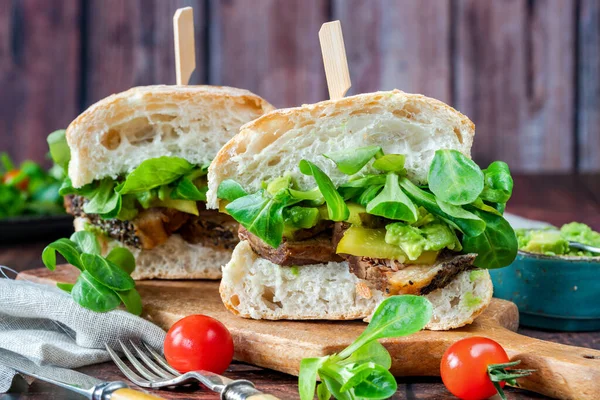Salatalık turşulu biftekli sandviç, ezilmiş avokado ve yeşil yaprak salatası.