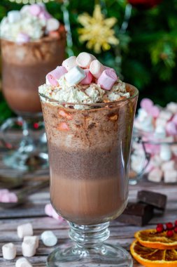 Krem şantili sıcak çikolata ve arka planda Noel ağacı olan şekerleme.