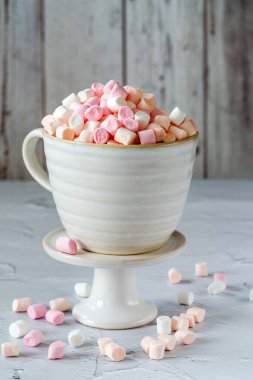 Beyaz masadaki bardakta mini marşmelovlar.