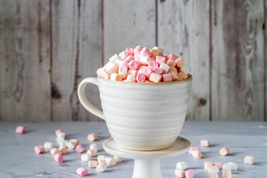 Beyaz masadaki bardakta mini marşmelovlar.