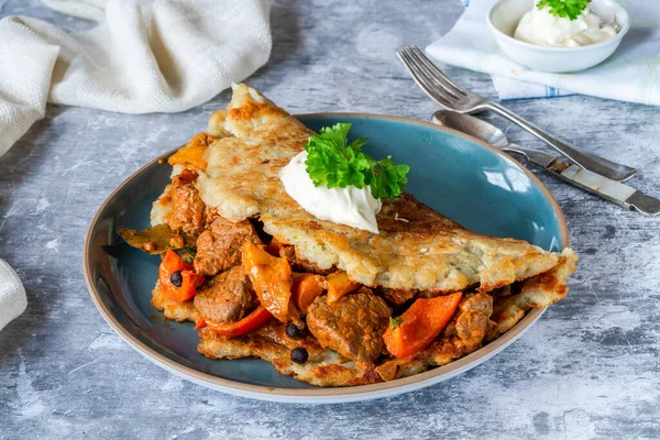 Traditional Hungarian goulash with potato pancake and cream