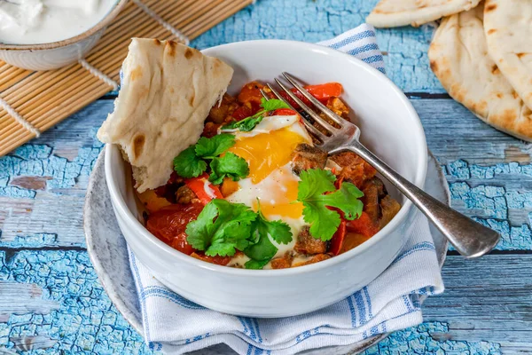 Shakshuka - classic North African and Middle Eastern dish of poached eggs in spiced tomato and pepper sauce