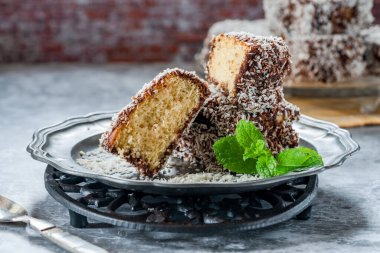 Lamington kek kareleri. Çikolata sosu ve kurutulmuş hindistan cevizli geleneksel Avustralya sünger kekleri.