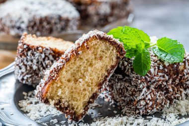 Lamington kek kareleri. Çikolata sosu ve kurutulmuş hindistan cevizli geleneksel Avustralya sünger kekleri.