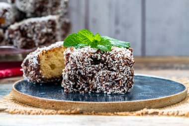 Lamington kek kareleri. Çikolata sosu ve kurutulmuş hindistan cevizli geleneksel Avustralya sünger kekleri.
