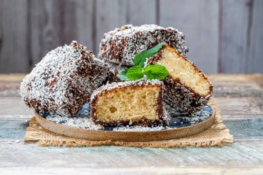 Lamington kek kareleri. Çikolata sosu ve kurutulmuş hindistan cevizli geleneksel Avustralya sünger kekleri.