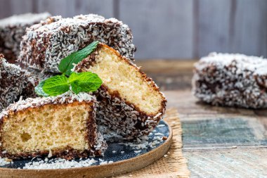 Lamington kek kareleri. Çikolata sosu ve kurutulmuş hindistan cevizli geleneksel Avustralya sünger kekleri.