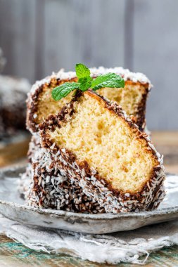 Lamington kek kareleri. Çikolata sosu ve kurutulmuş hindistan cevizli geleneksel Avustralya sünger kekleri.