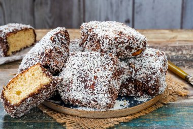 Lamington kek kareleri. Çikolata sosu ve kurutulmuş hindistan cevizli geleneksel Avustralya sünger kekleri.