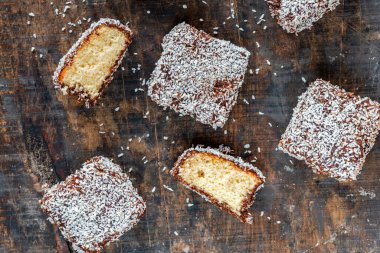 Lamington kek kareleri. Çikolata sosu ve kurutulmuş hindistan cevizli geleneksel Avustralya sünger kekleri.