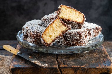 Lamington kek kareleri. Çikolata sosu ve kurutulmuş hindistan cevizli geleneksel Avustralya sünger kekleri.