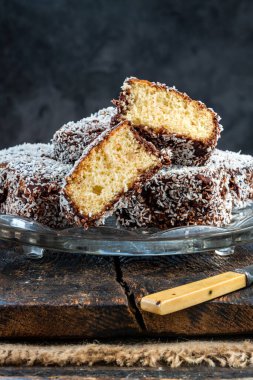 Lamington kek kareleri. Çikolata sosu ve kurutulmuş hindistan cevizli geleneksel Avustralya sünger kekleri.