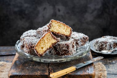 Lamington kek kareleri. Çikolata sosu ve kurutulmuş hindistan cevizli geleneksel Avustralya sünger kekleri.