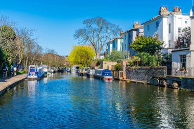 LONDON, İngiltere - 29 Mart 2021: Londra 'nın Camden bölgesindeki Regent Kanalı' na demirlemiş dar tekne ve tekneler. Kanal Paddington 'u Limehouse Havzası' na ve Thames Nehri 'ni Doğu Londra' ya bağlıyor.