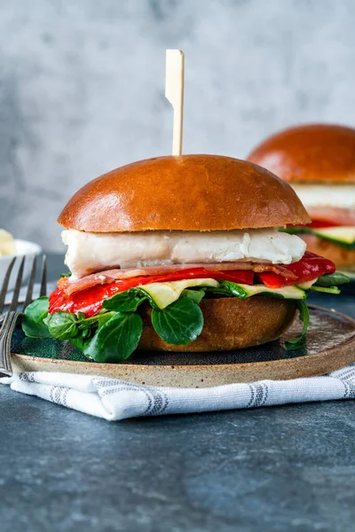 Grilled halibut sandwich in brioche bun with bacon, red romano pepper, courgette and lamb\'s lettuce