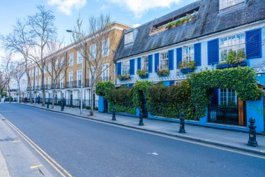 LONDON, İngiltere - 11 Nisan 2021: Notting Hill 'deki yerleşim sokağının manzarası, geniş Viktorya dönemi konak evleri ve lüks alışveriş ve restoranların teraslarıyla bilinen zengin ve modaya uygun bir bölge