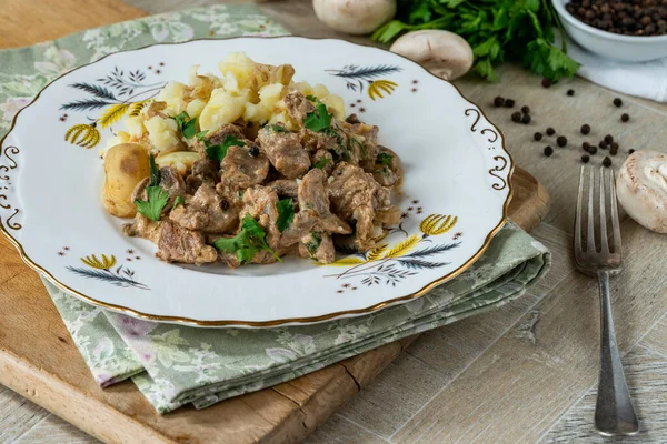 Beef goulash with creamy mushroom and black peppercorn sauce and crushed boiled potatoes