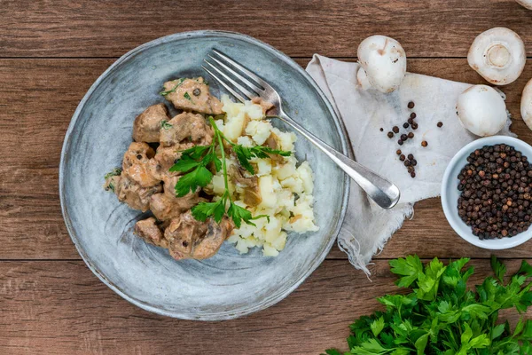 Beef goulash with creamy mushroom and black peppercorn sauce and crushed boiled potatoes - overhead view