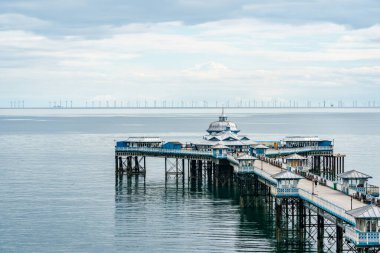 LLANDUDNO, WALES - 4 Temmuz 2021 Llandudno Rıhtımı ve 576 megawattlık Gwynt-y-Mor açık deniz rüzgar çiftliği. Dünyanın en büyük beşinci rüzgâr çiftliği Galler açıklarında yer almaktadır.