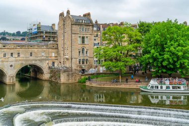 BATH, İngiltere - 27 Haziran 2021: Bath 'daki Avon Nehri üzerindeki Pulteney Köprüsü manzarası, Somerset' in en büyük şehri, Roma tarafından inşa edilmiş hamamlarından ve isimlerinden tanınır..