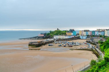 TENBY, WALES - 28 Haziran 2021: Tenby limanındaki renkli evler, Galler 'in Pembrokeshire şehrinde, Carmarthen Körfezi' nin batı yakasındaki bir sahil kasabası. 