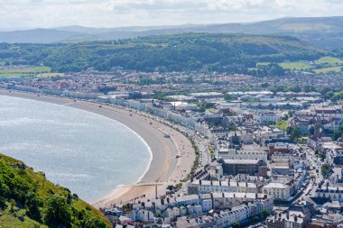 LLANDUDNO, WALES - 3 Temmuz 2021: Great Orme Burnu 'ndan otellerin oluşturduğu Llandudno kıvrımlı gezinti alanı. Llandudno, Galler 'in en büyük sahil beldesidir..